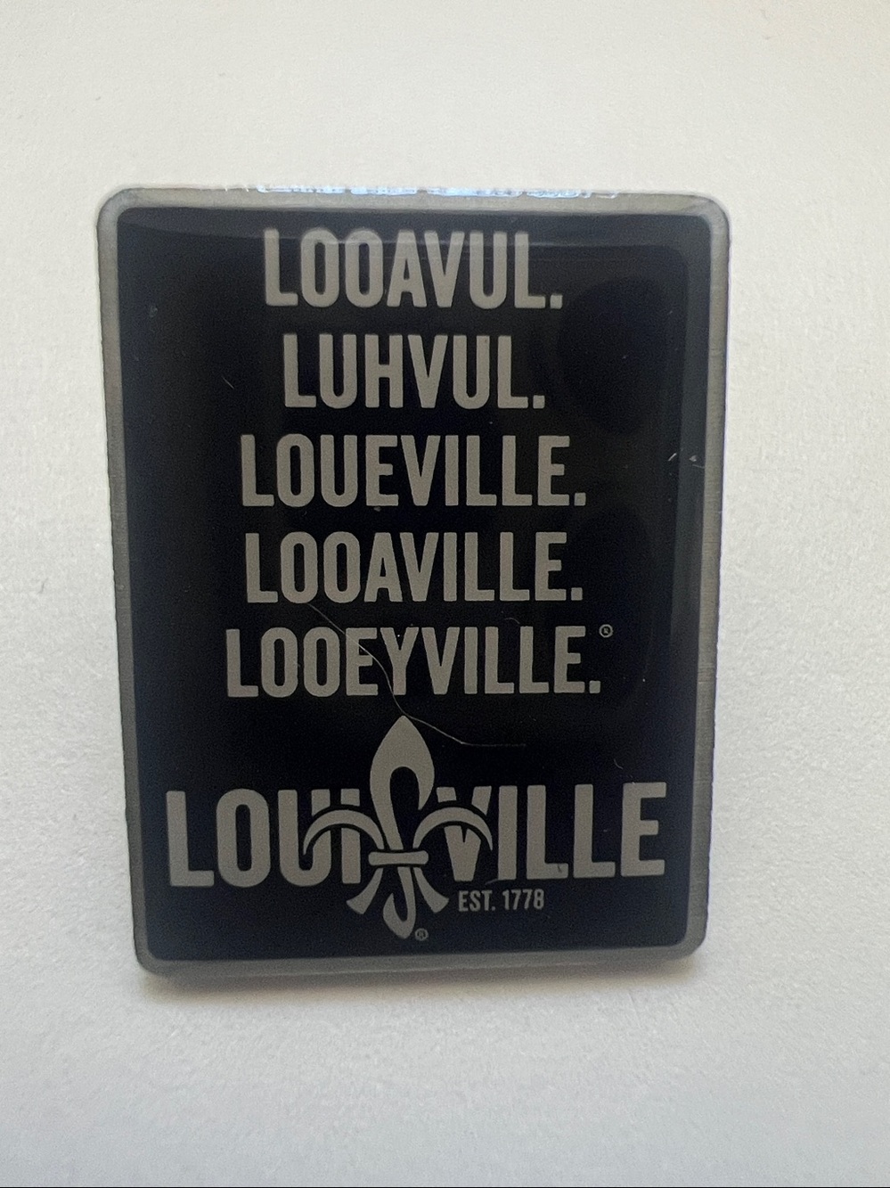 Louisville lapel pin features popular phonetic mispronunciations of "Louisville”